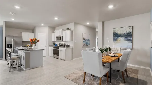 a kitchen with white cabinets and chairs