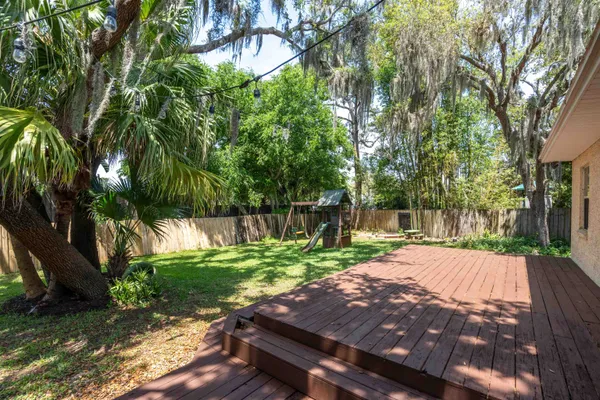 a view of a backyard with table and chairs a fire pit and a large tree