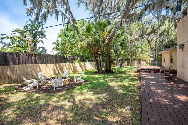 a view of a backyard with table and chairs potted plants and a large tree