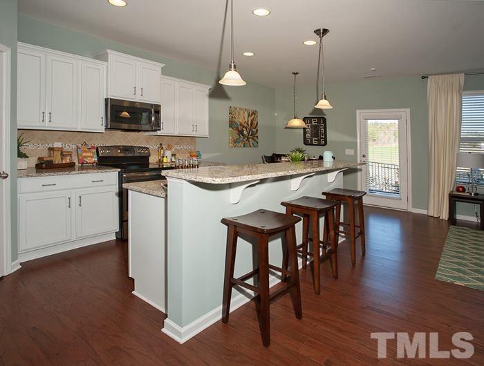 3003 Bluegrove Road Raleigh, NC 27610 - Photo 5 of 25 a kitchen with stainless steel appliances granite countertop a stove a sink a microwave a dining table and chairs with wooden floor