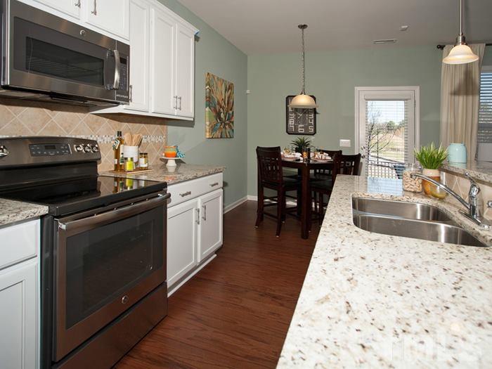 3003 Bluegrove Road Raleigh, NC 27610 - Photo 9 of 25 a kitchen with stainless steel appliances kitchen island granite countertop a stove a sink and a microwave
