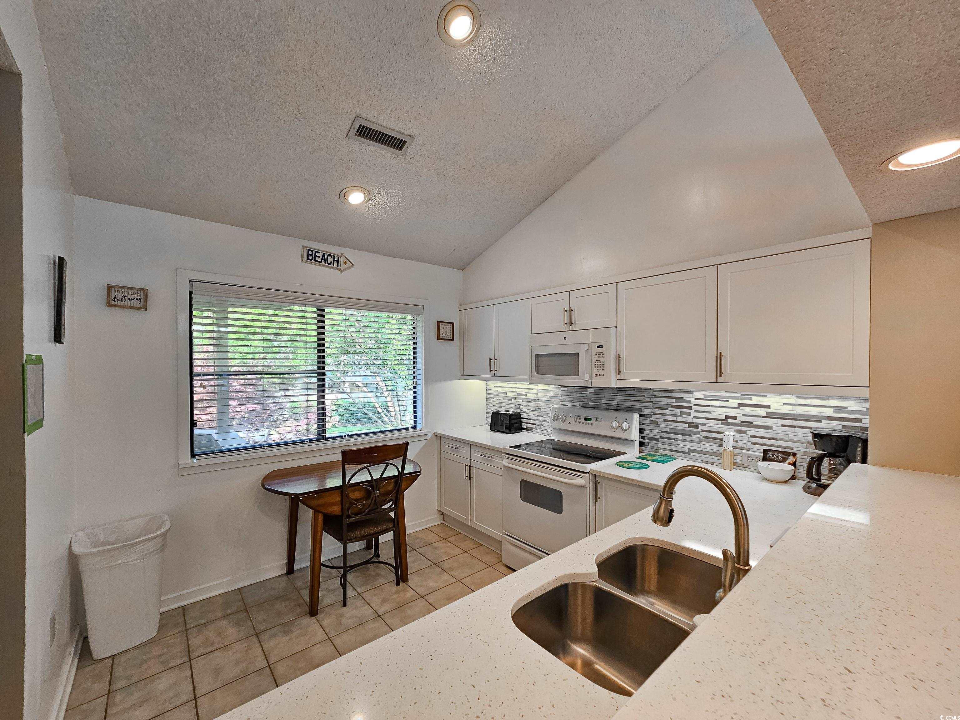 210 Westleton Drive, Unit 13D Myrtle Beach, SC 29572 - Photo 11 of 40 Kitchen with white appliances, a sink, a textured ceiling, tasteful backsplash, and light tile patterned floors