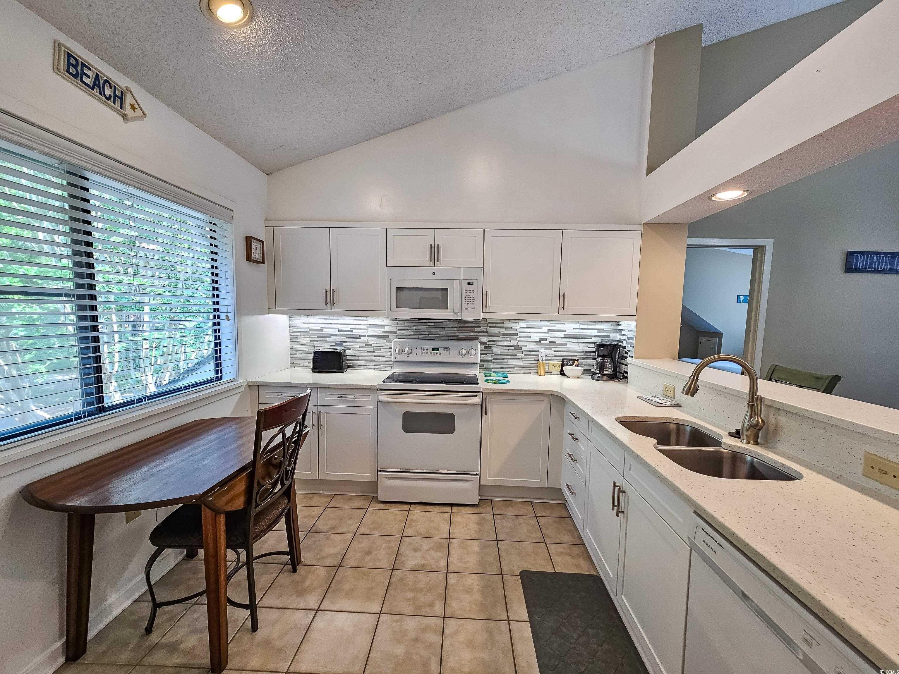 210 Westleton Drive, Unit 13D Myrtle Beach, SC 29572 - Photo 12 of 40 Kitchen featuring white appliances, a sink, a textured ceiling, backsplash, and white cabinets