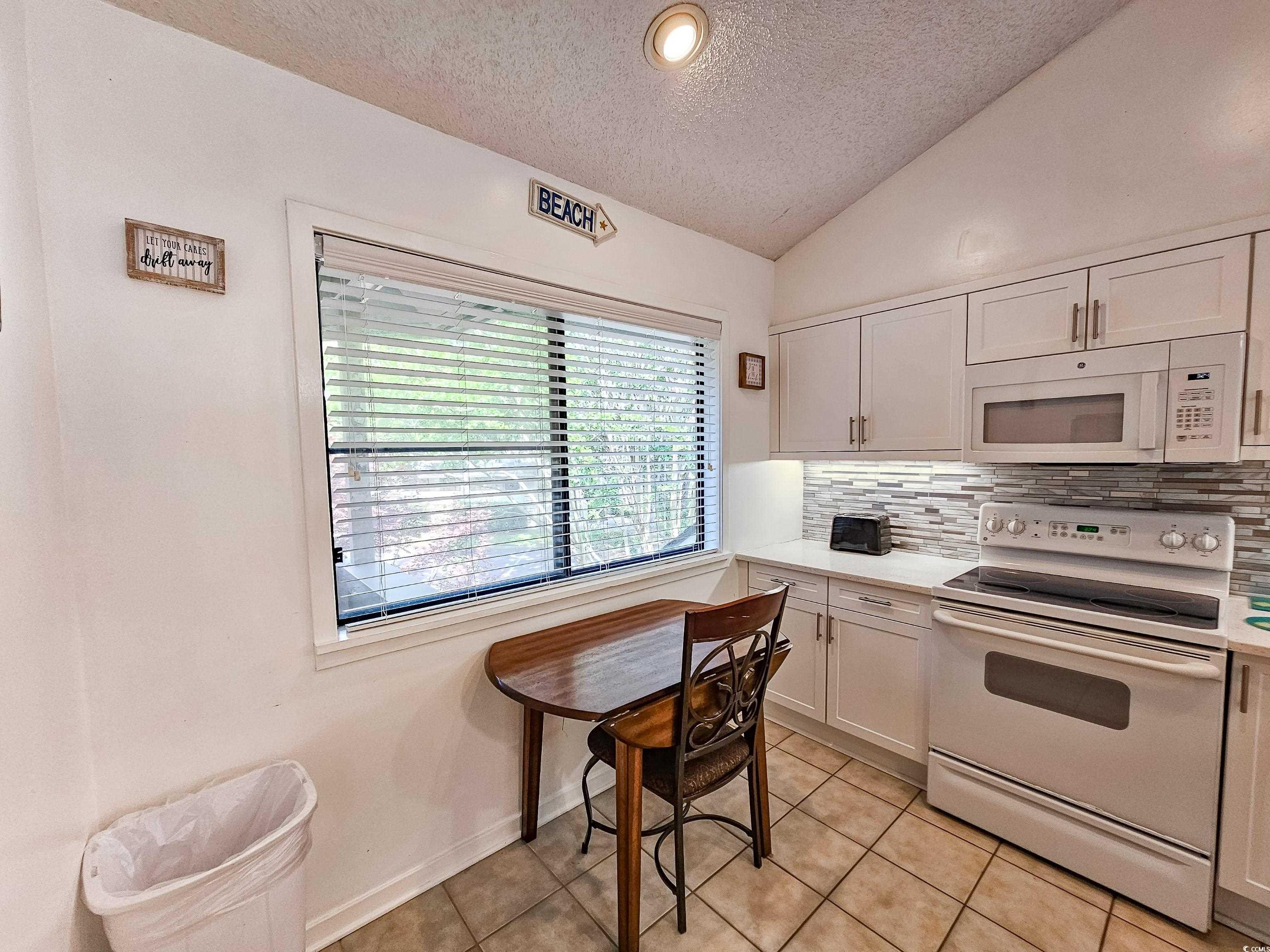 210 Westleton Drive, Unit 13D Myrtle Beach, SC 29572 - Photo 13 of 40 Kitchen featuring white appliances, a textured ceiling, decorative backsplash, light countertops, and light tile patterned flooring