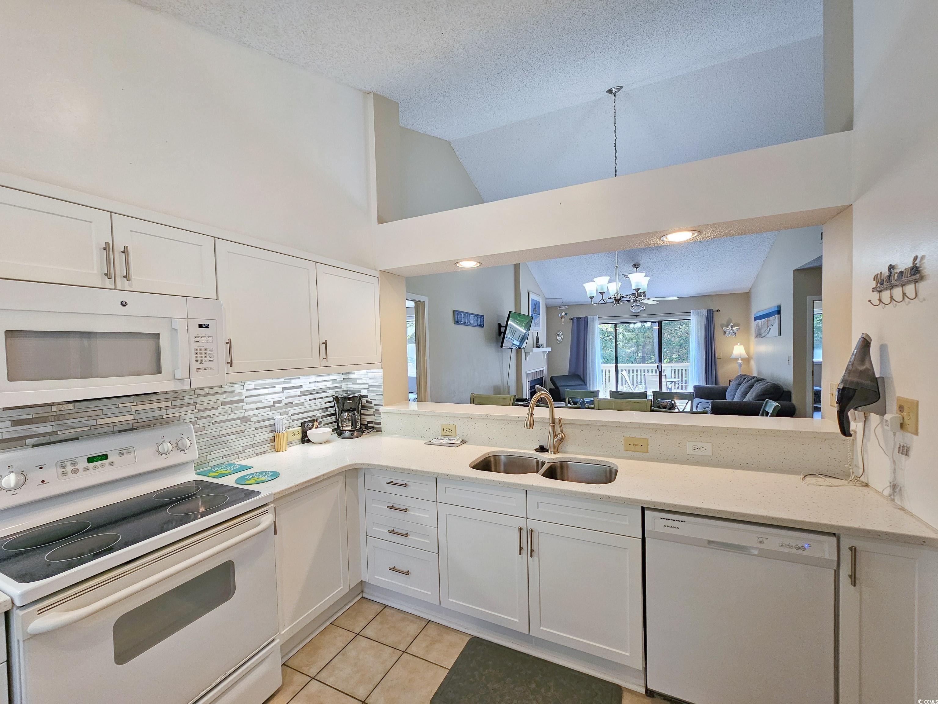 210 Westleton Drive, Unit 13D Myrtle Beach, SC 29572 - Photo 14 of 40 Kitchen featuring white appliances, a sink, a chandelier, vaulted ceiling, and light tile patterned floors