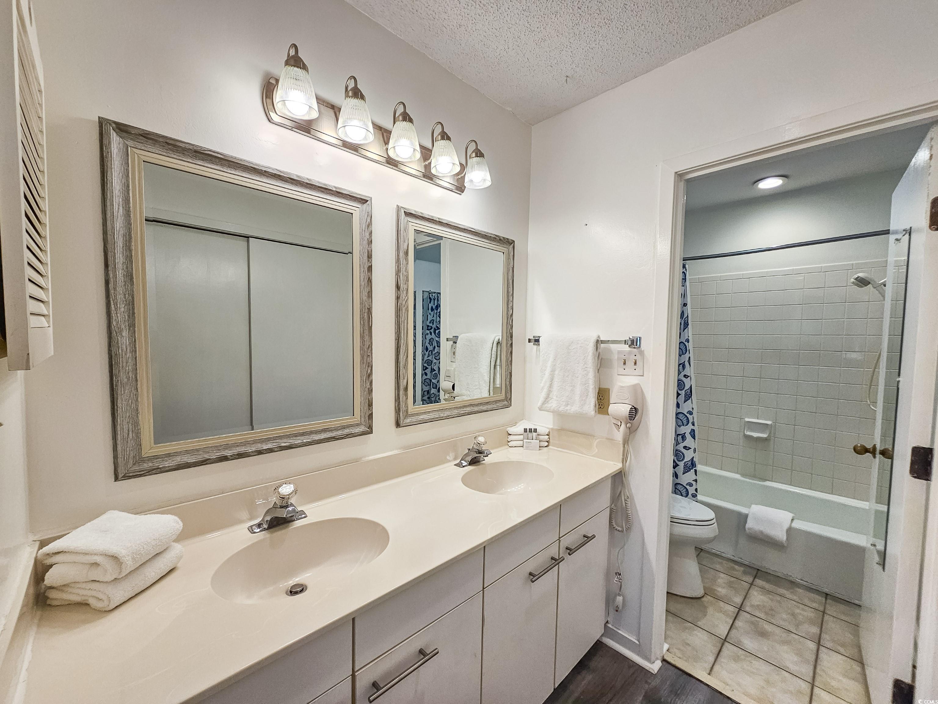 210 Westleton Drive, Unit 13D Myrtle Beach, SC 29572 - Photo 24 of 40 Bathroom featuring double vanity, toilet, shower / bathtub combination with curtain, and a textured ceiling