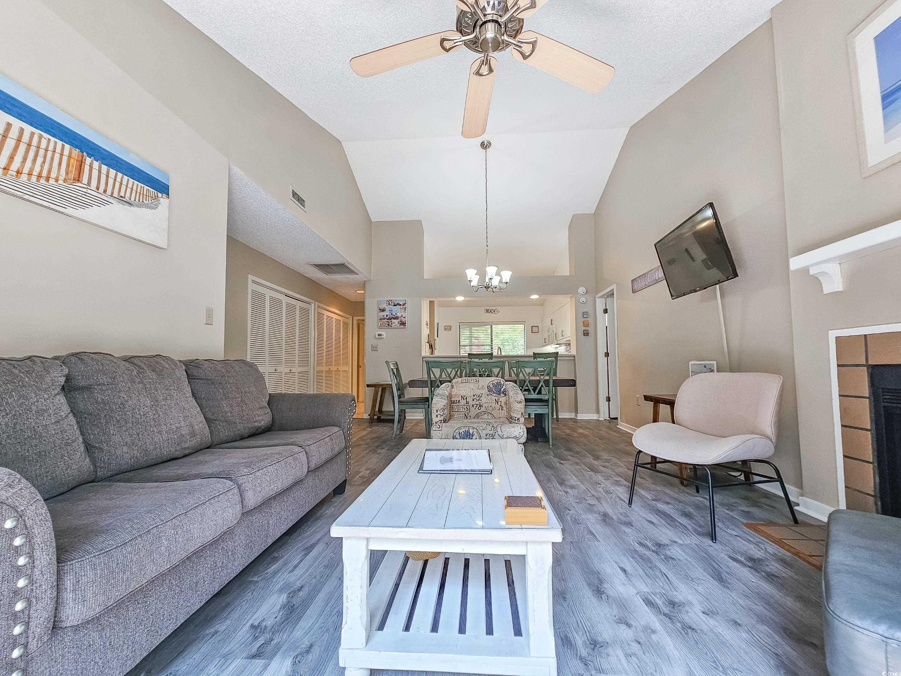210 Westleton Drive, Unit 13D Myrtle Beach, SC 29572 - Photo 7 of 40 Living area with a chandelier, wood finished floors, high vaulted ceiling, a ceiling fan, and a tile fireplace