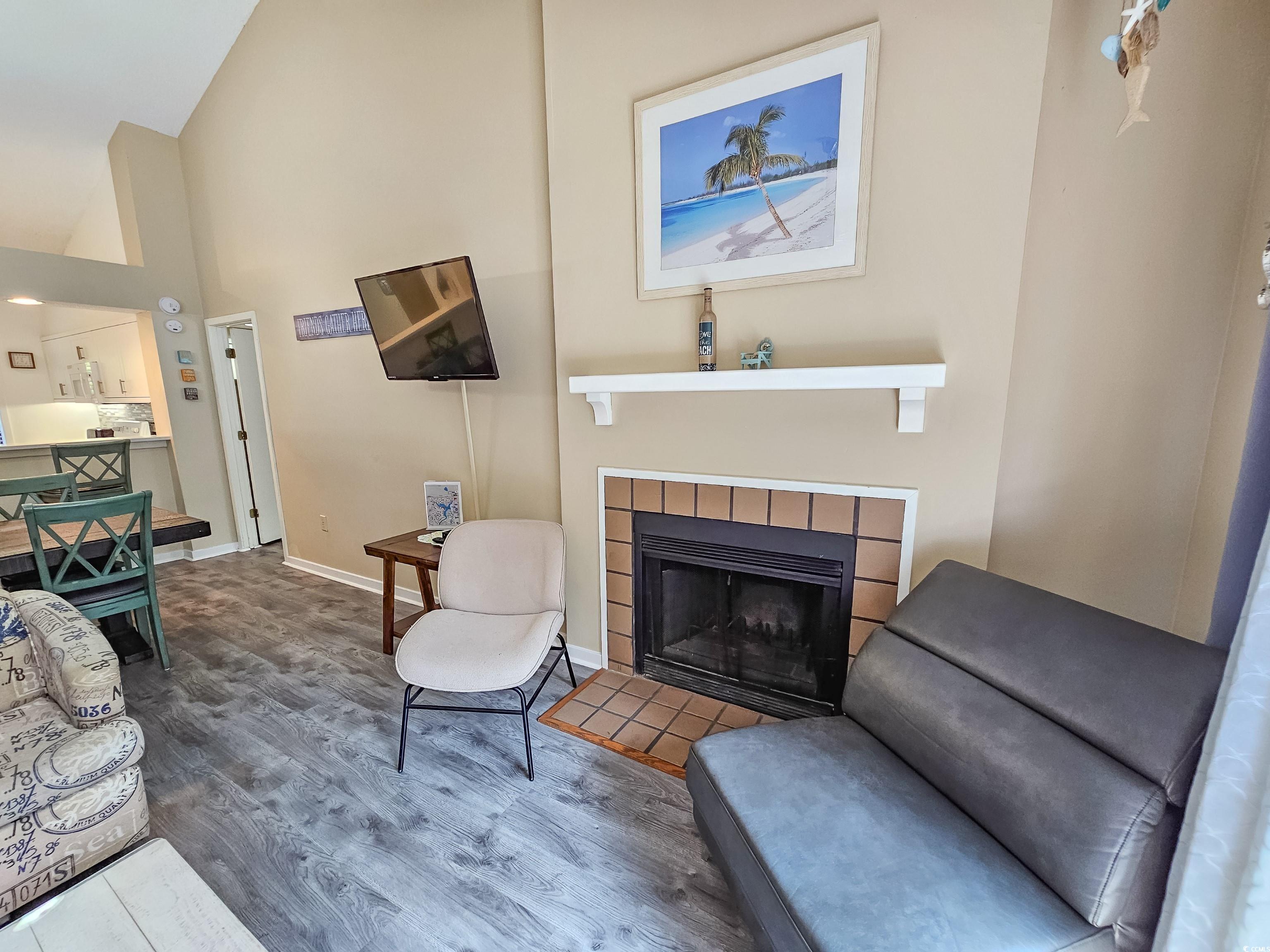 210 Westleton Drive, Unit 13D Myrtle Beach, SC 29572 - Photo 8 of 40 Living room featuring wood finished floors, a tiled fireplace, high vaulted ceiling, and baseboards