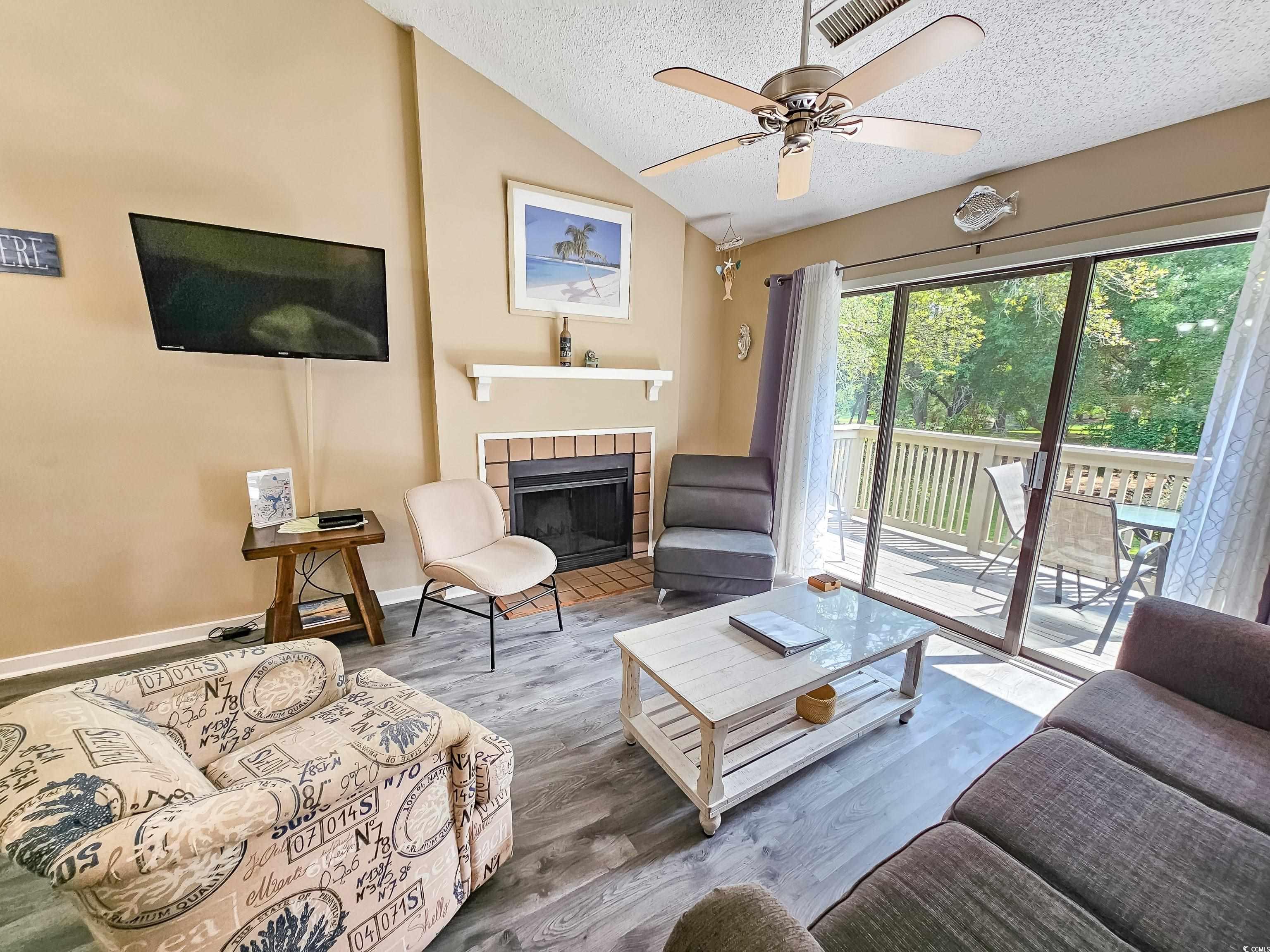 210 Westleton Drive, Unit 13D Myrtle Beach, SC 29572 - Photo 10 of 40 Living room featuring a textured ceiling, vaulted ceiling, a tile fireplace, a ceiling fan, and wood finished floors