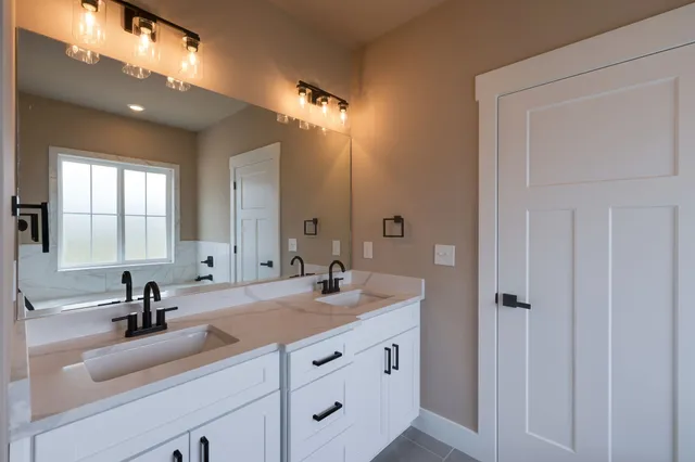 a bathroom with double vanity sinks and a mirror