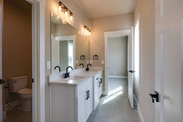 a en suite bathroom with a granite countertop sink toilet and a mirror