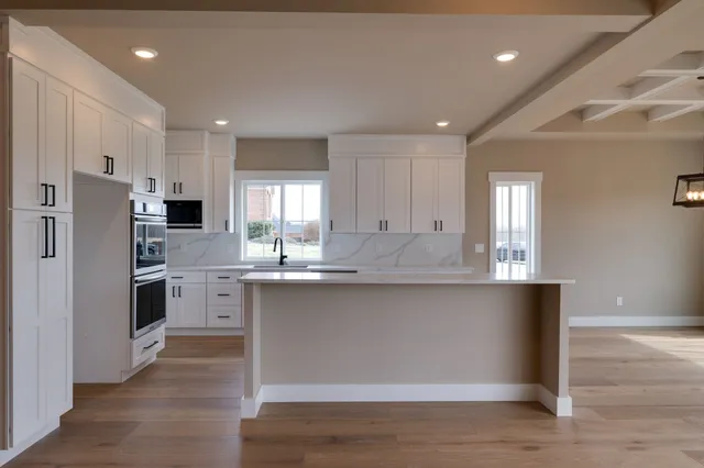 a kitchen with stainless steel appliances granite countertop a refrigerator a sink dishwasher a stove and white cabinets with wooden floor