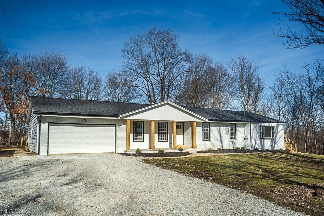 Ranch-style home featuring a front yard, a garage, and a porch