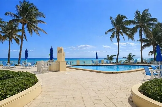 a view of a swimming pool with a lawn chairs and palm trees