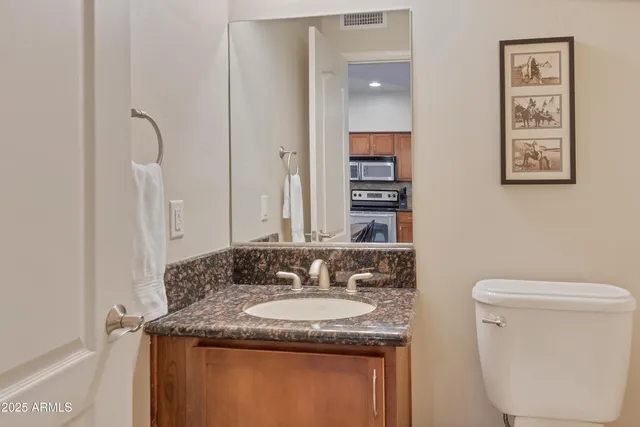 a bathroom with a granite countertop sink a toilet and a mirror