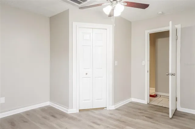 an empty room with wooden floor closet and chandelier fan
