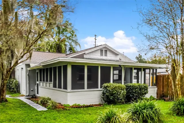 a view of a white house with a large window and flower plants with yard in front of main door
