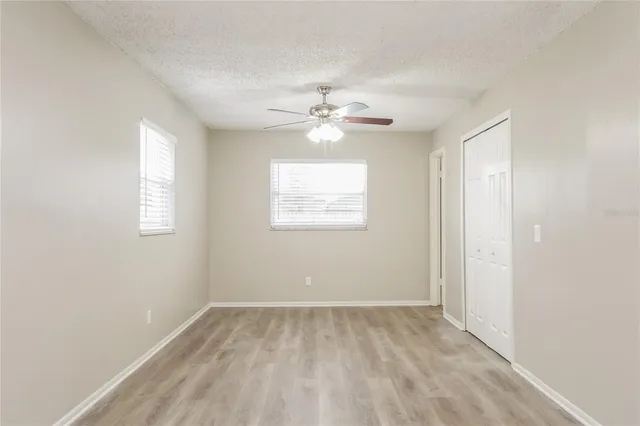 an empty room with a window and a ceiling fan