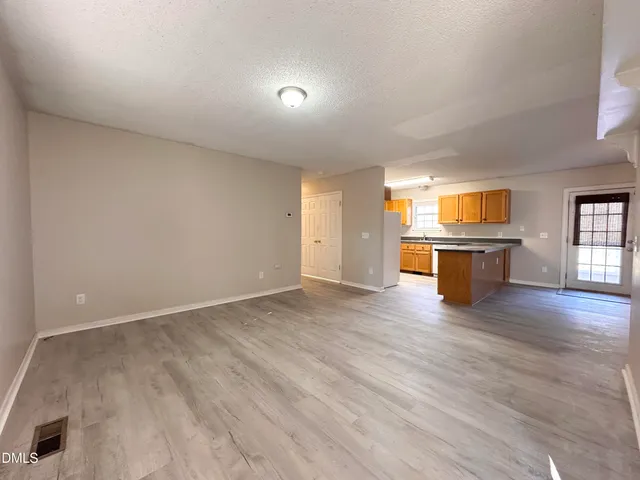 an empty room with wooden floor and bathroom view