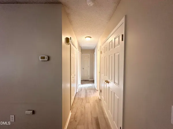 a view of a hallway with wooden floor and a bathroom