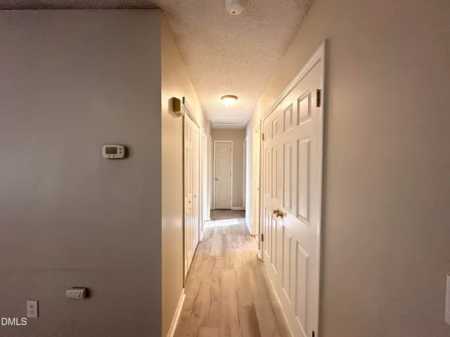 a view of a hallway with wooden floor and a bathroom