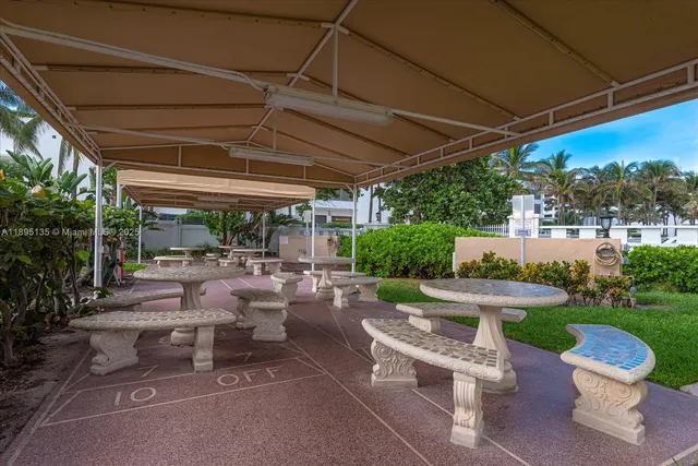 a view of a patio with chairs and a table and chairs under an umbrella