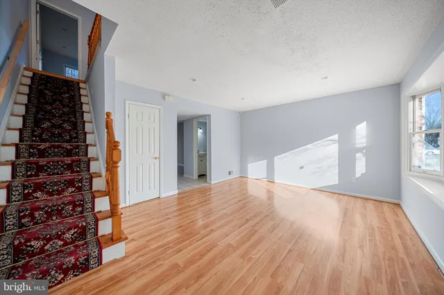 a view of empty room with wooden floor and window
