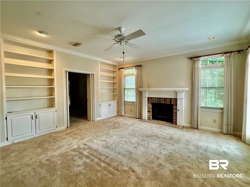 3932 Mcgregor Court Mobile, AL 36608 - Photo 2 of 9 Unfurnished living room featuring carpet flooring, built in features, ceiling fan, a fireplace, and ornamental molding