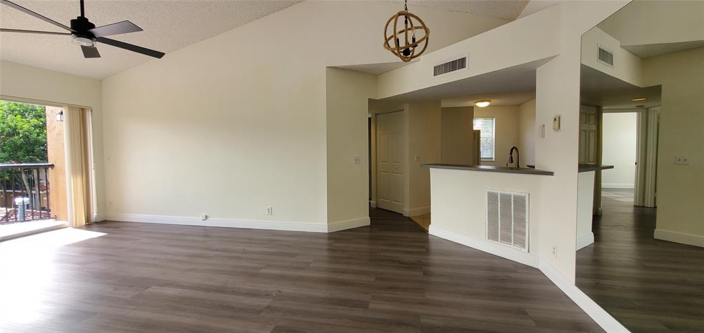 8781 Wiles Road, Unit 308 Coral Springs, FL 33067 - Photo 6 of 24 an empty room with wooden floor and a hallway