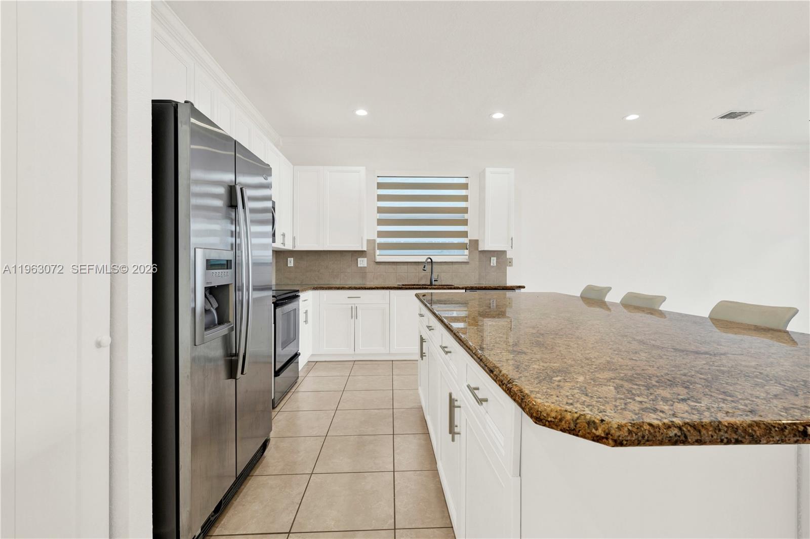23824 Southwest 107th Place Homestead, FL 33032 - Photo 7 of 33 a kitchen with kitchen island granite countertop a sink and a refrigerator