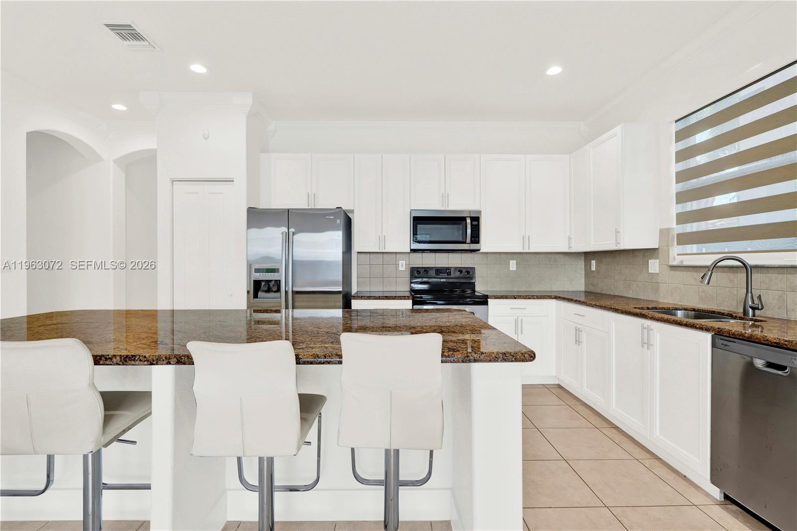 23824 Southwest 107th Place Homestead, FL 33032 - Photo 9 of 33 a kitchen with stainless steel appliances kitchen island granite countertop a sink and cabinets