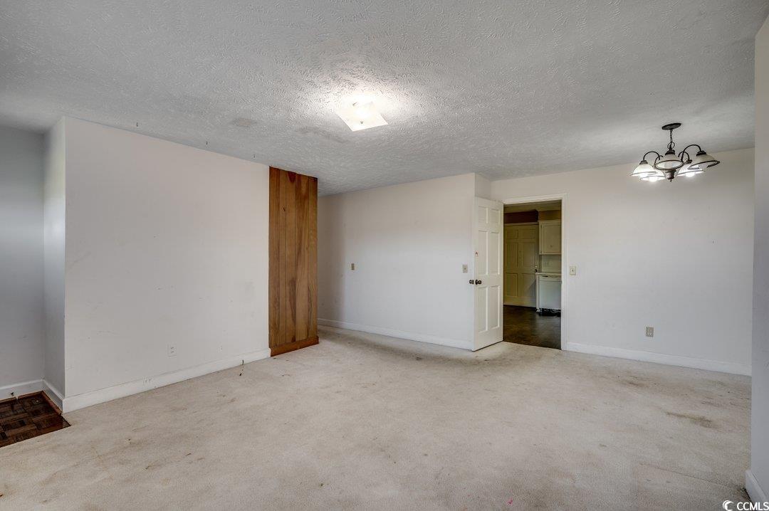 3701 South Green Sea Road Loris, SC 29569 - Photo 3 of 31 Empty room featuring a textured ceiling, an inviting chandelier, and carpet flooring