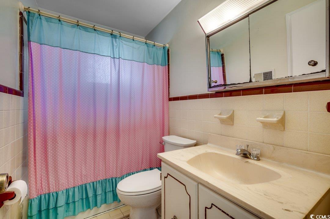 3701 South Green Sea Road Loris, SC 29569 - Photo 6 of 31 Full bathroom with vanity, shower / tub combo with curtain, tile walls, tile patterned flooring, and toilet