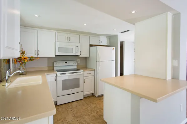 a kitchen with a refrigerator sink and white cabinets
