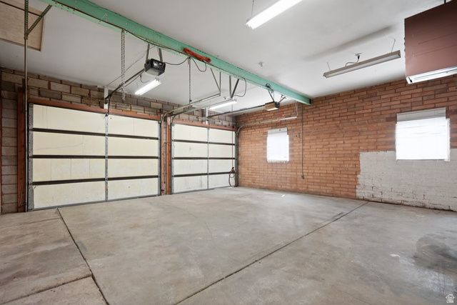 673 East 700 South Springville, UT 84663 - Photo 37 of 43 Spacious two-car garage featuring a concrete floor, exposed brick walls, two overhead garage doors, and ample overhead lighting