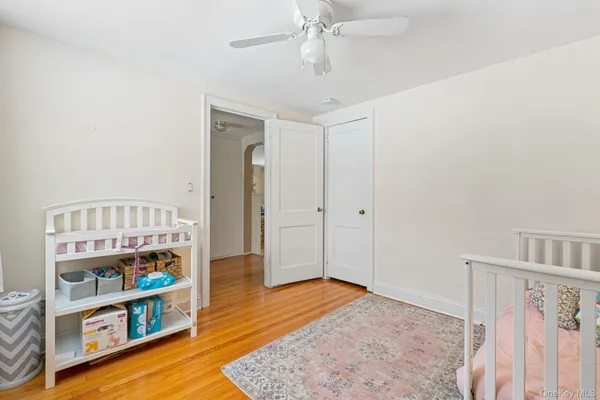 a view of a bedroom with baby crib and wooden floor