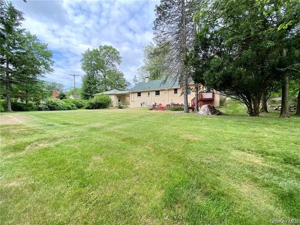 a view of a house with a big yard and large trees
