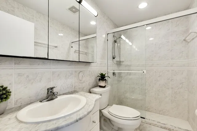 a bathroom with a sink a toilet a mirror and shower