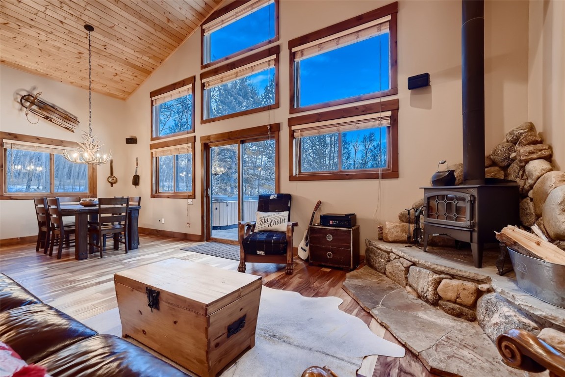 490 Adventure Road Alma, CO 80420 - Photo 7 of 28 Living room featuring a wood stove, light hardwood / wood-style flooring, high vaulted ceiling, wooden ceiling, and an inviting chandelier