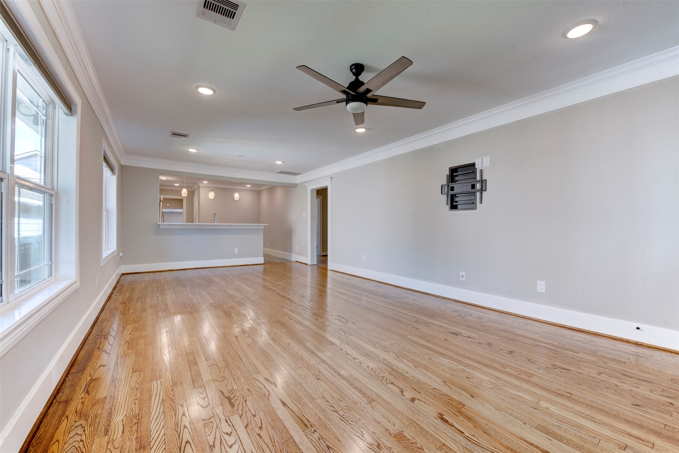 109 Dresden Street Houston, TX 77012 - Photo 5 of 43 Spacious living area with hardwood floors, large windows for natural light, and an open layout leading to a kitchen with a breakfast bar. Features recessed lighting and a ceiling fan.