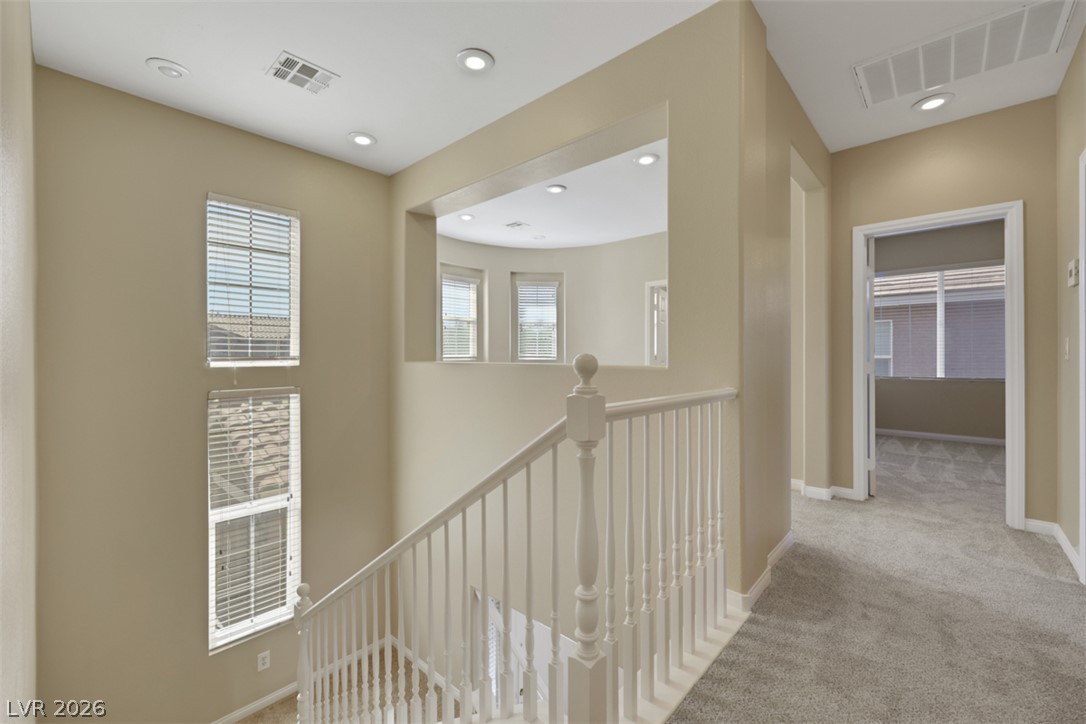 10328 Hawk Ravine Street Las Vegas, NV 89178 - Photo 23 of 55 An inviting upper-level landing with plush carpeting and natural light from tall windows.