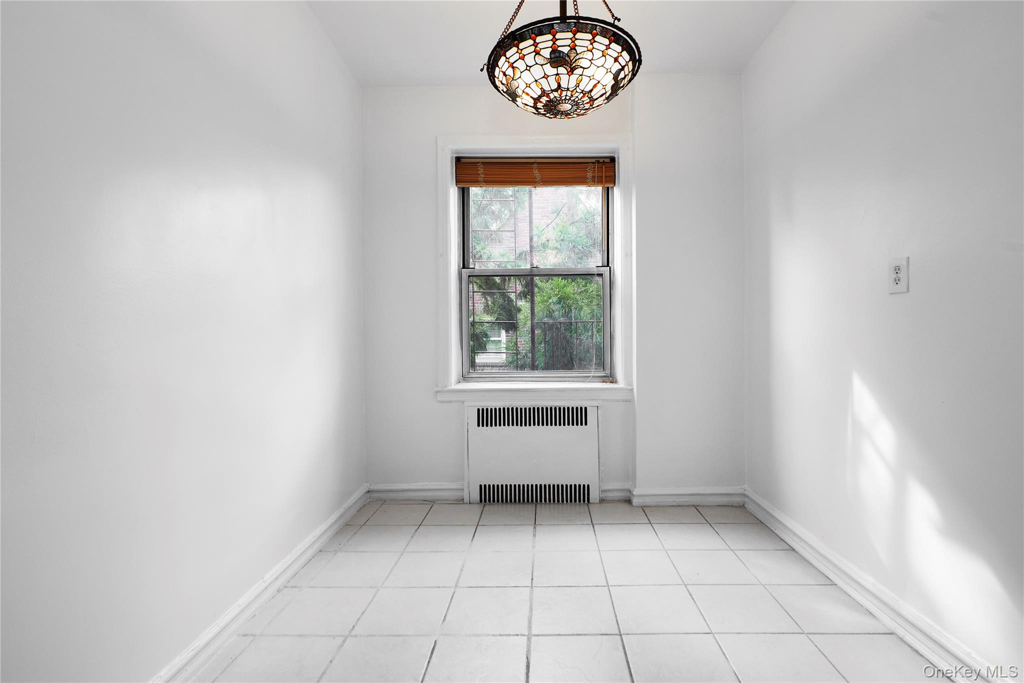 86-10 34th Avenue, Unit 225 Queens, NY 11372 - Photo 5 of 11 Unfurnished room featuring radiator heating unit and light tile patterned floors