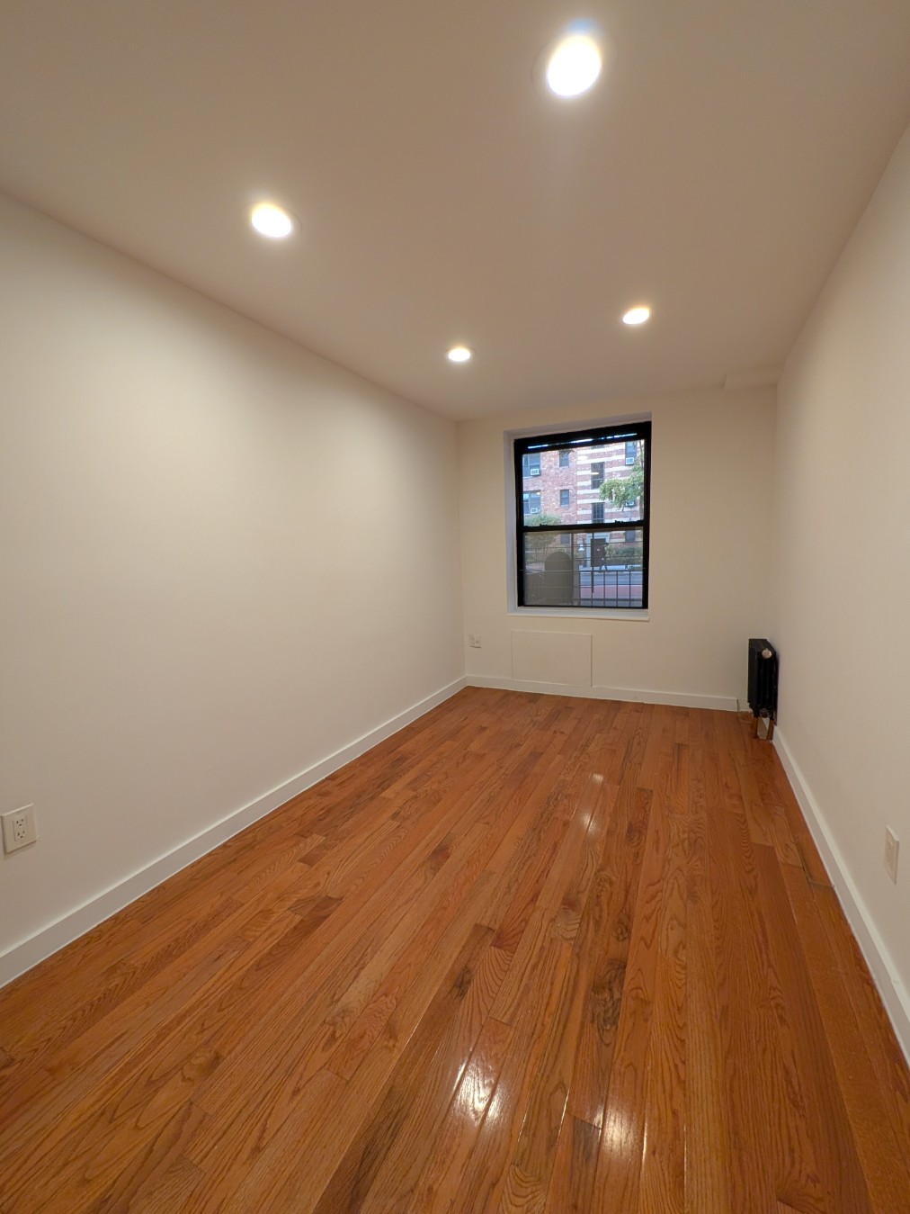 416 West 23rd Street, Unit 1A Manhattan, NY 10011 - Photo 7 of 9 an empty room with wooden floor and windows