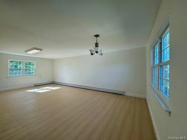 an empty room with wooden floor cabinet and windows