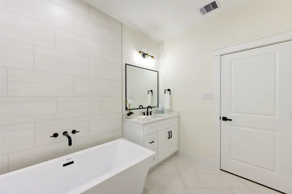 a bathroom with a tub a sink and mirror