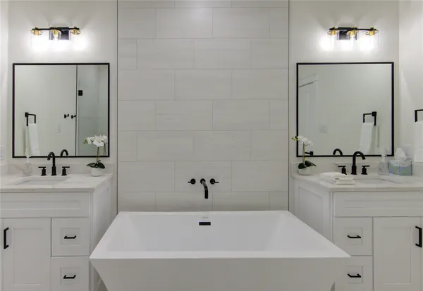 a bathroom with a bathtub a sink a mirror and vanity
