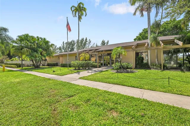 a view of a house with a big yard and palm trees
