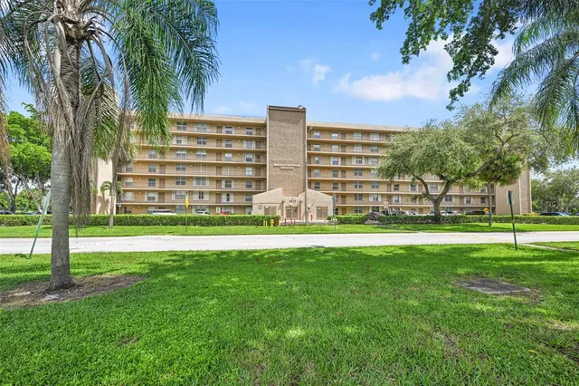a view of a apartment with a big yard and palm trees