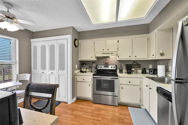 a kitchen with stainless steel appliances kitchen island granite countertop a stove a sink dishwasher and white cabinets with wooden floor