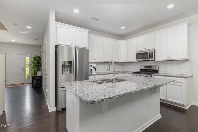 a kitchen with a refrigerator a microwave a sink and cabinets